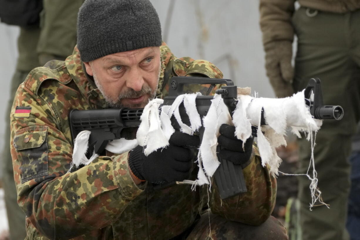 A member of the Georgian Legion, a paramilitary unit formed mainly by ethnic Georgian volunteers to fight against the Russian forces in Ukraine in 2014, shows how to use a gun to civilians during their training in Kyiv, Ukraine, Saturday, Feb. 19, 2022. Separatist leaders in eastern Ukraine have ordered a full military mobilization amid growing fears in the West that Russia is planning to invade the neighboring country. The announcement on Saturday came amid a spike in violence along the line of contact between Ukrainian forces and the pro-Russia rebels in recent days.