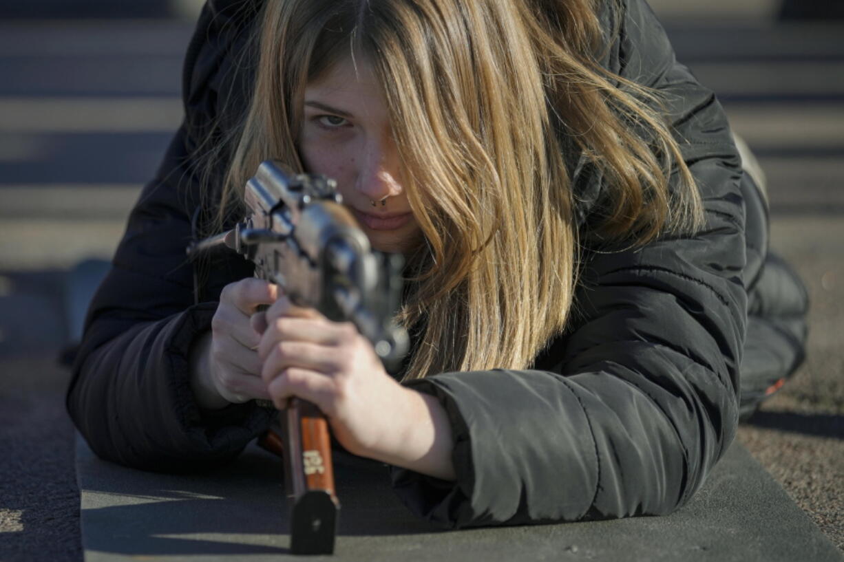 A young woman holds a weapon during a basic combat training for civilians, organized by the Special Forces Unit Azov, of Ukraine's National Guard, in Mariupol, Donetsk region, eastern Ukraine, Sunday, Feb. 13, 2022. The United States is evacuating almost all of the staff from its embassy in Kyiv as Western intelligence officials warn that a Russian invasion of Ukraine is increasingly imminent.