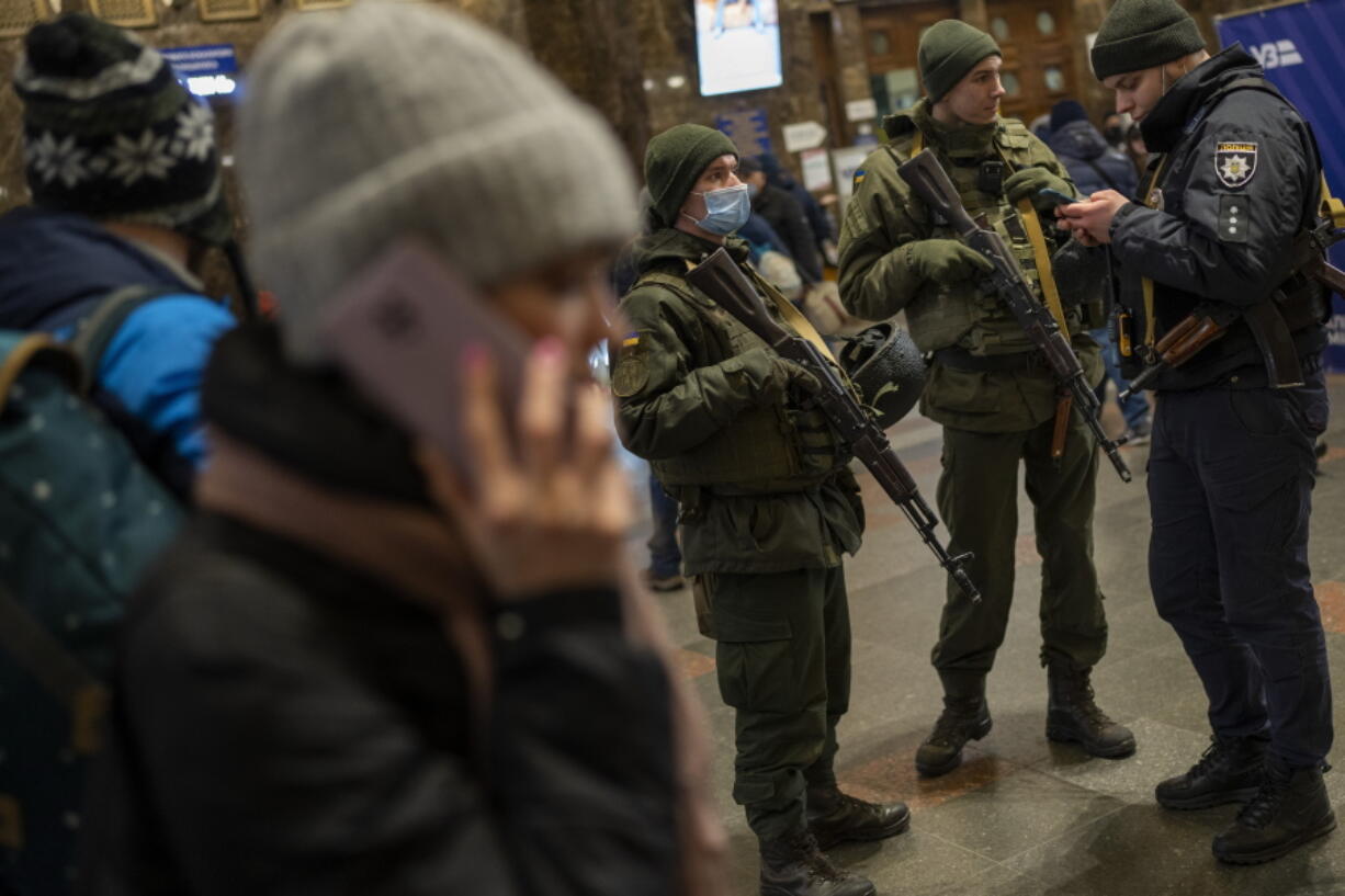 Ukrainian soldiers stand guard as people try to leave at the Kyiv train station, Ukraine, Thursday, Feb. 24, 2022. Russian troops have launched their anticipated attack on Ukraine. Big explosions were heard before dawn in Kyiv, Kharkiv and Odesa as world leaders decried the start of an Russian invasion that could cause massive casualties and topple Ukraine's democratically elected government.