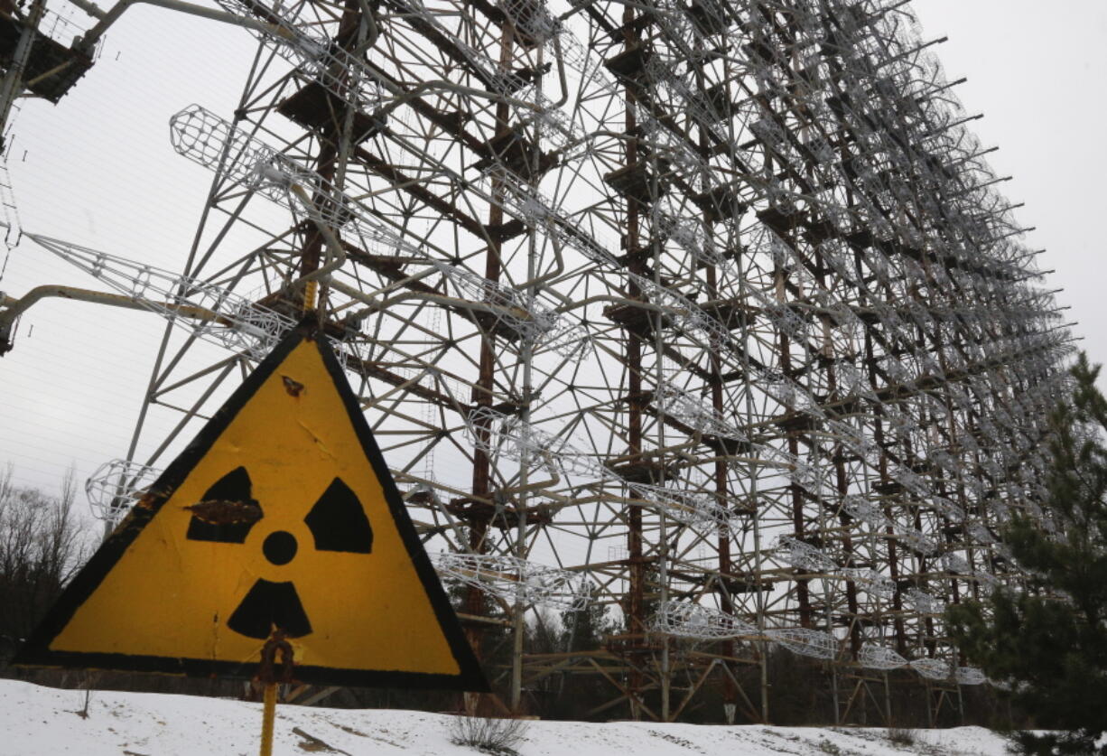 FILE - A Soviet-era top secret object Duga, an over-the-horizon radar system once used as part of the Soviet missile defense early-warning radar network, seen behind a radioactivity sign in Chernobyl, Ukraine, on Nov. 22, 2018. Among the most worrying developments on an already shocking day, as Russia invaded Ukraine on Thursday, was warfare at the Chernobyl nuclear plant, where radioactivity is still leaking from history's worst nuclear disaster 36 years ago.