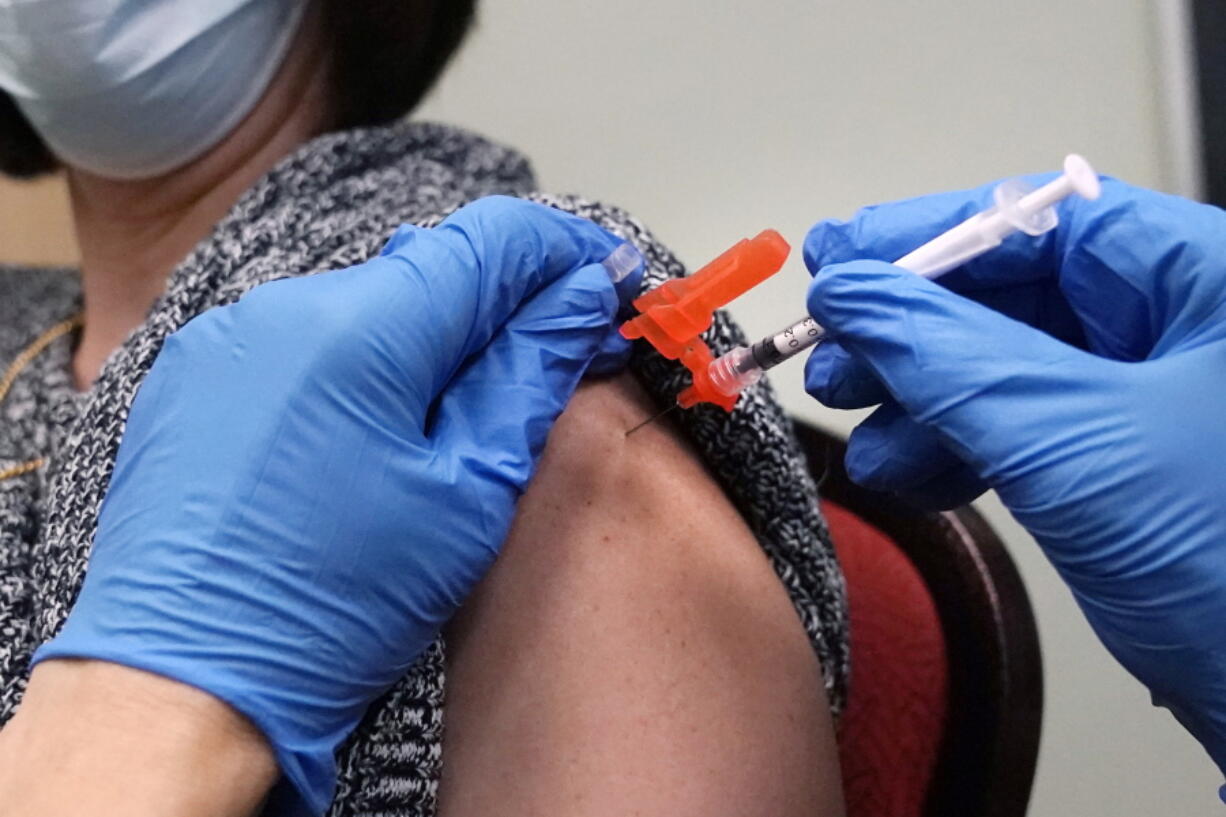 FILE - A woman receives a COVID-19 vaccine injection by a pharmacist at a clinic in Lawrence, Mass., on Wednesday, Dec. 29, 2021. One of the first studies to look at the performance of COVID-19 booster shots during the recent omicron wave of illnesses found a surprising decline in effectiveness after only four months. The findings are based on data from hospitals and urgent care centers in 10 states.