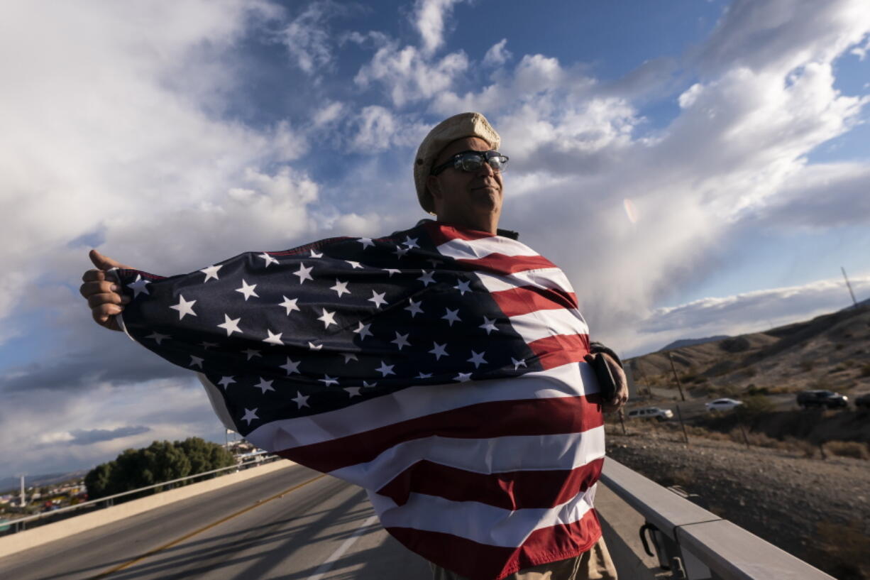 FILE - John Hiickman cheers on a convoy of truckers heading toward Washington to protest COVID-19 mandates, Feb. 23, 2022, in Needles, Calif. Omicron is fading away, and so are Americans' worries about COVID-19. Fewer Americans now say they're concerned they'll be infected compared with January following the rise and fall of the wildly contagious coronavirus variant. That's according to a new poll from The Associated Press-NORC Center for Public Affairs Research.