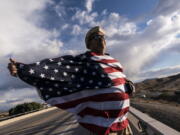 FILE - John Hiickman cheers on a convoy of truckers heading toward Washington to protest COVID-19 mandates, Feb. 23, 2022, in Needles, Calif. Omicron is fading away, and so are Americans' worries about COVID-19. Fewer Americans now say they're concerned they'll be infected compared with January following the rise and fall of the wildly contagious coronavirus variant. That's according to a new poll from The Associated Press-NORC Center for Public Affairs Research.