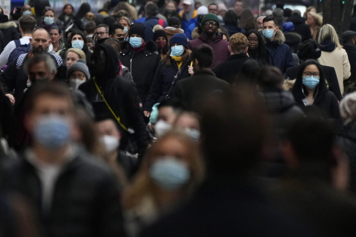 FILE - Shoppers walk down Oxford Street, Europe's busiest shopping street, in London, Dec. 23, 2021. The British government confirmed Saturday Feb. 19, 2022, that people with the coronavirus will not be legally required to self-isolate starting next week, as part of a plan for "living with COVID" that is also likely to see testing for the virus scaled back.