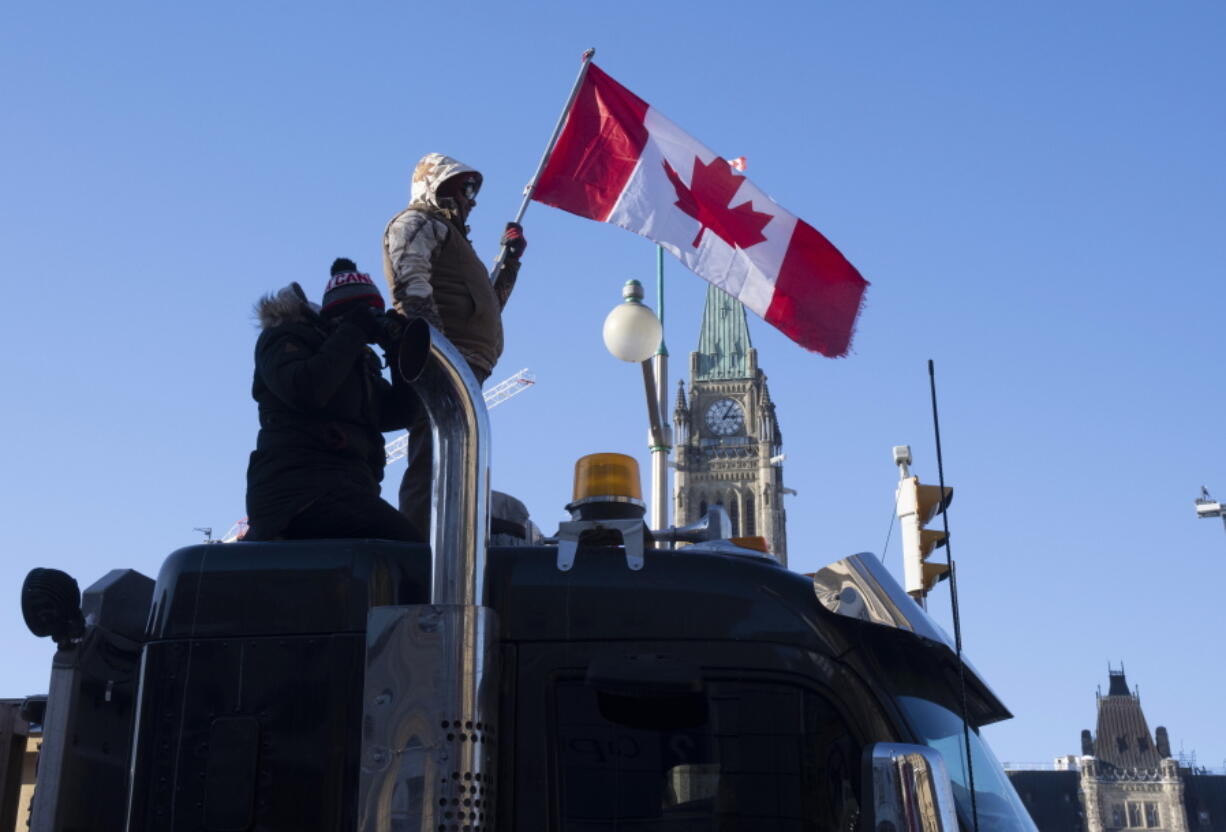 Protesters stand on the top of a truck parked in front of the Parliament buildings during a demonstration against COVID-19 restrictions, in Ottawa, Ontario, Saturday, Feb. 5, 2022.