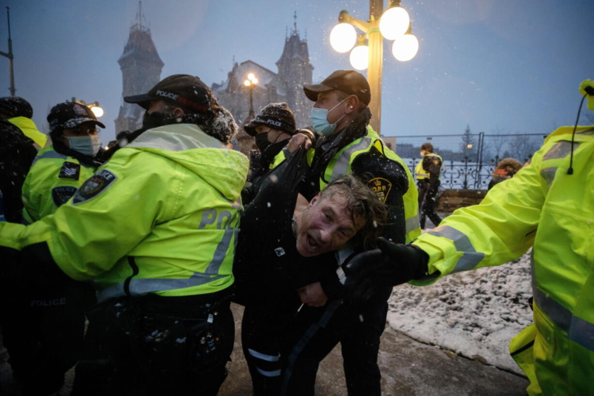 A man is arrested by police as protesters and supporters gather as a protest against COVID-19 measures that has grown into a broader anti-government protest continues to occupy downtown Ottawa, Ontario, on Thursday, Feb. 17, 2022.