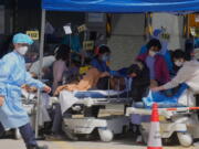 Patients in hospital beds wait at temporary holding area outside Caritas Medical Centre in Hong Kong, Monday, Feb. 28, 2022.