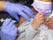 A 5-year-old girl receives her first dose of the Pfizer COVID-19 vaccine from a nurse in the cafeteria of the Pittsburgh Langley K-8 school in Pittsburgh on Saturday, Jan. 8, 2022. COVID-19 vaccines for kids under 5 may be available in the U.S. as early as March 2022, but there are several hurdles still to clear.