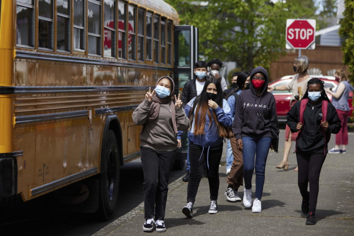 FILE -- Students get off the bus at Roseway Heights Middle School on the first day of in-person hybrid learning, April 19, 2021, in Portland, Ore. The governors of Connecticut, Delaware, New Jersey and Oregon this week announced plans to lift mask mandates in schools by the end of February or March, as COVID-19's omicron surge fades.