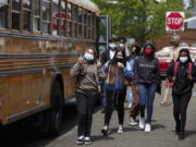 FILE -- Students get off the bus at Roseway Heights Middle School on the first day of in-person hybrid learning, April 19, 2021, in Portland, Ore. The governors of Connecticut, Delaware, New Jersey and Oregon this week announced plans to lift mask mandates in schools by the end of February or March, as COVID-19's omicron surge fades.