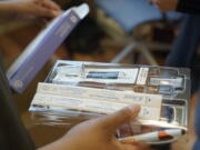 Kristin Travis, a community outreach doula, holds a home COVID-19 test kit Thursday, Feb. 3, 2022, while picking up supplies at Open Arms Perinatal Services before going out to visit some of her clients in Seattle. The kits were provided by the King County Public Health Dept. and distributed by community-based organizations as a way of providing more accessible testing and faster results. (AP Photo/Ted S.