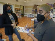 Kristin Travis, right, a community outreach doula, picks up home COVID-19 test kits Thursday, Feb. 3, 2022, from Stacey Silver, left, a program administrator at Open Arms Perinatal Services before going out to visit some of her clients in Seattle. The kits were provided by the King County Public Health Dept. and distributed by community-based organizations as a way of providing more accessible testing and faster results. (AP Photo/Ted S.