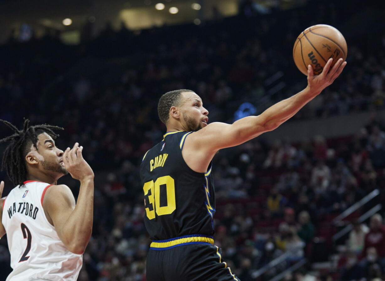 Golden State Warriors guard Stephen Curry, right, shoots in front of Portland Trail Blazers forward Trendon Watford during the first half of an NBA basketball game in Portland, Ore., Thursday, Feb. 24, 2022.