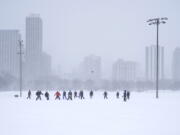 Men play football on a soccer field in Chicago's Lincoln Park Wednesday, Feb. 2, 2022. A major winter storm with millions of Americans in its path brought a mix of rain, freezing rain and snow to the middle section of the United States as airlines canceled hundreds of flights, governors urged residents to stay off roads and schools closed campuses.