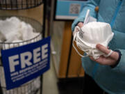 A shopper holds a handful of free N95 respirator masks available in the pharmacy at the QFC store in southeast Vancouver on Thursday morning, Feb. 3, 2022.