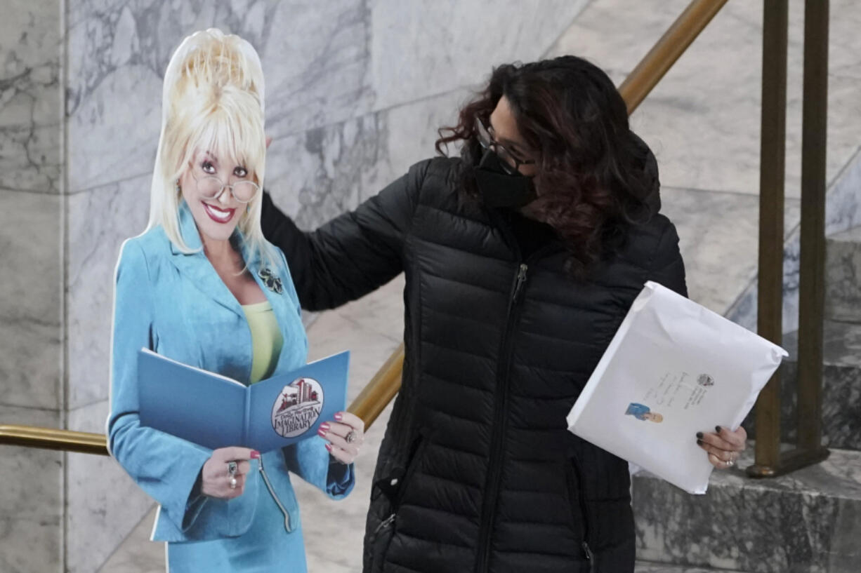 Rep. Monica Stonier, D-Vancouver, holds a photo cut-out of singer Dolly Parton as she walks to the floor of the House on Jan. 26 at the Capitol in Olympia. Stonier co-sponsored a measure that establishes statewide Parton's Imagination Library, which gives children age 5 and under free books each month. (Ted S.