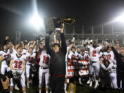 Camas head coach Jon Eagle hoists the trophy into the air after Saturday?s win in the Class 4A state championship game against Bothell at Mount Tahoma High School in Tacoma on Dec. 7, 2019.