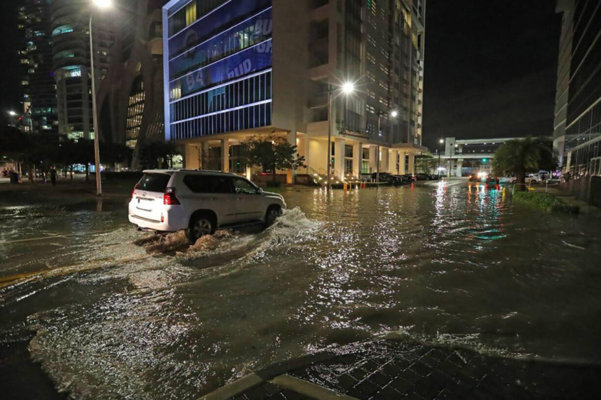 A car drives through a flooded Northeast 11th Street and Biscayne Boulevard in downtown Miami on Feb. 16, 2021.