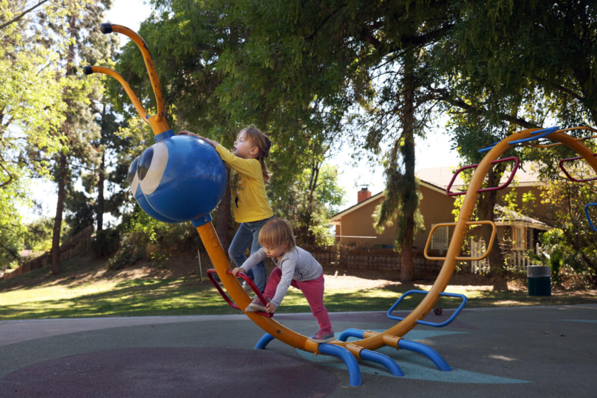 Sisters Carmen, left, and Sylvie Hawks, right, play on a structure at Porter Ridge Park, also known as E.T. Park, in the Porter Ranch neighborhood of Los Angeles on Tuesday, March 8, 2022. The City Council will consider a motion to rename the park "E.T. Park" after parts of the movie "E.T. the Extra-Terrestrial" were shot there.