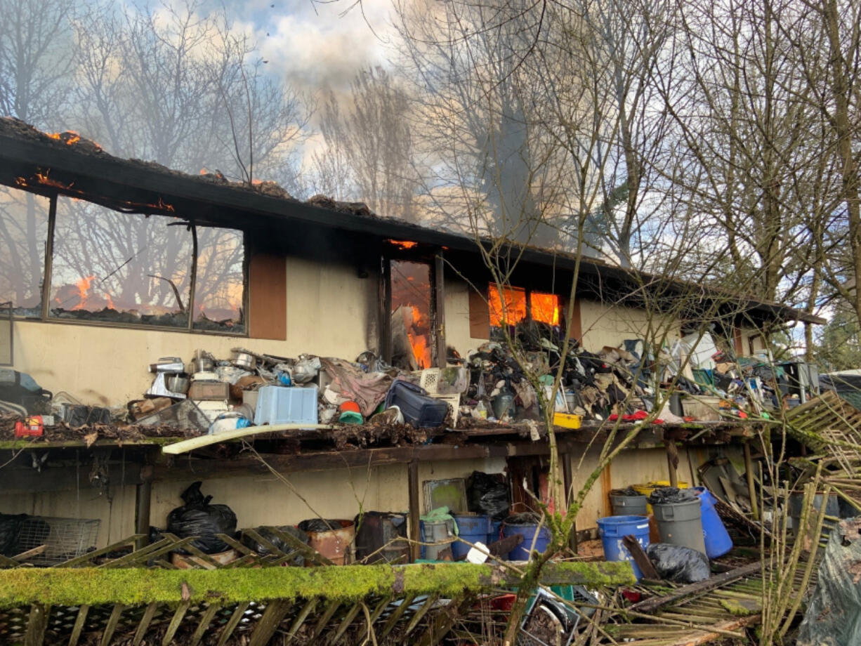 A house burns Wednesday afternoon in the Cherry Grove area west of Battle Ground. Clark-Cowlitz Fire Rescue said the house was too cluttered for firefighters to go inside to extinguish the fire.