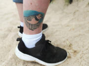 A tattoo of Rose, an endangered Great Lakes piping plover, is inked on the leg of Dori Levine, a volunteer for the U.S. Fish and Wildlife Service, as she observes Rose and her mate, Monty, with their four recently hatched chicks July 10, 2021, at Montrose Beach in Chicago. (Jose M.