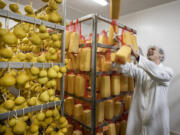 Dan Wavrin, cheesemaker for his family's Ferndale Farmstead, playfully flips provolone cheese blocks back up onto the aging rack, Feb. 4, 2022. To the left is the smoky Schamorza cheese.