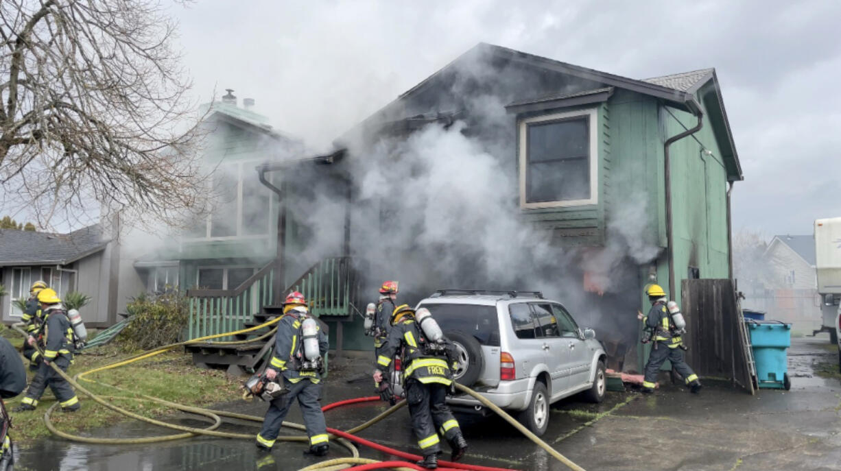 Vancouver Fire Department firefighters extinguish a garage and house fire in east Vancouver's Mountain View neighborhood. One person suffered a minor burn injury, the fire agency said.
