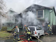 Vancouver Fire Department firefighters extinguish a garage and house fire in east Vancouver's Mountain View neighborhood. One person suffered a minor burn injury, the fire agency said.