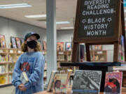 Eighth-grader Nola Bouffard looks over the selection of books as part of the diversity reading challenge in the library at Jason Lee Middle School in Hazel Dell.