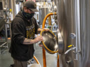 Brewer Josh McKinley installs a gasket into a fermentation tank at 54-40 Brewing Co. in Washougal. The brewery has been picked up for statewide distribution.