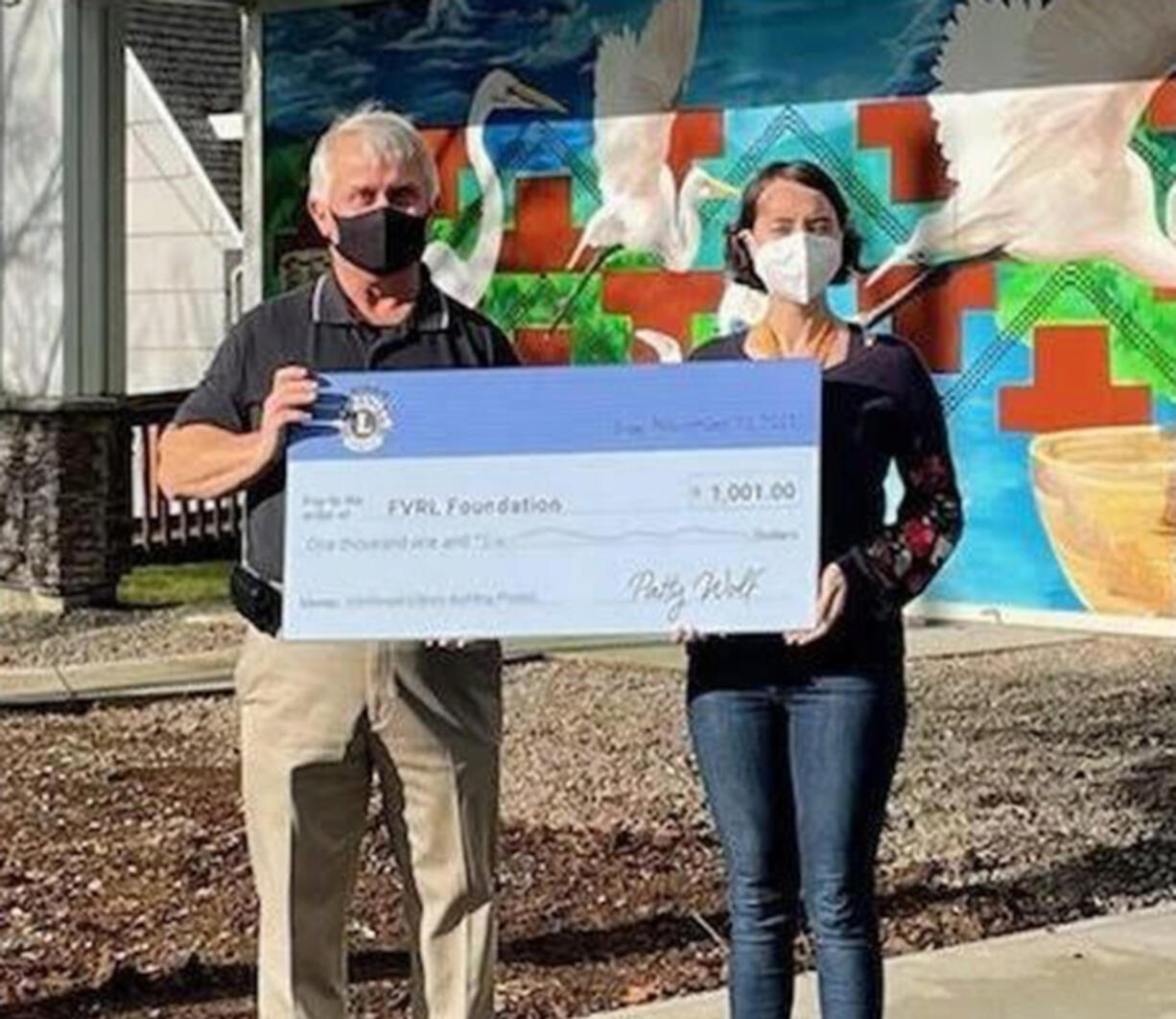 Camas Lions Club President Brian Scott presents Washougal Community Library Branch Manager Rachael Ries with a $1,001 check to help fund the new library building.