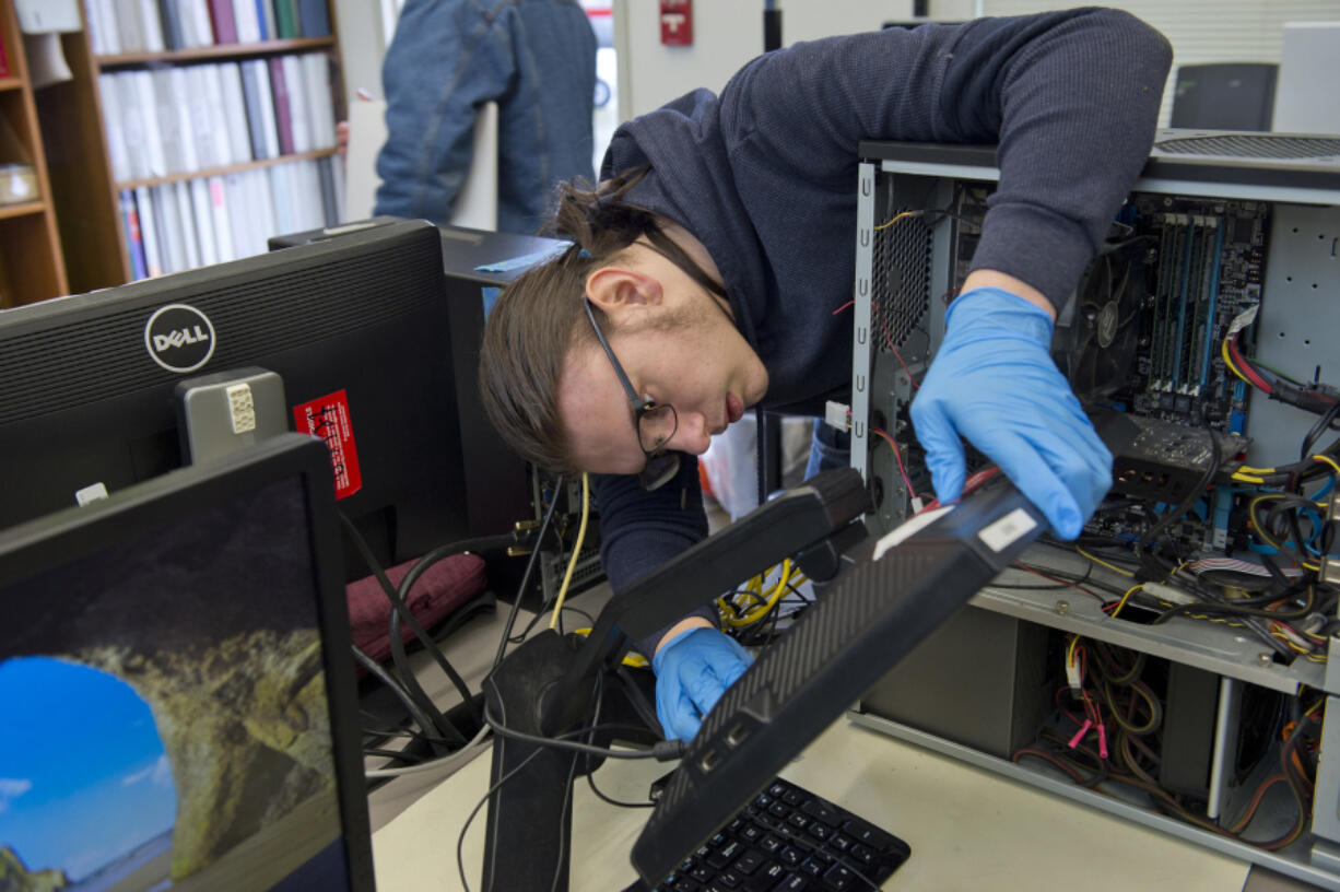 Senior Ethan Zanoli, the marketing manager for Cascadia Technical Academy's Information Technology Program, tests a monitor that was donated Saturday during the program's annual Electronic Waste Recycling Event. At top are harvested computer parts that were dropped off Saturday. This year marks the event's 10th anniversary.