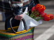 A shopper carries a basket with fresh tulips Saturday at the Vancouver Farmers Market.