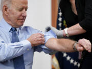 President Joe Biden rolls up his sleeve before receiving his second COVID-19 booster shot in the South Court Auditorium on the White House campus, Wednesday, March 30, 2022, in Washington.