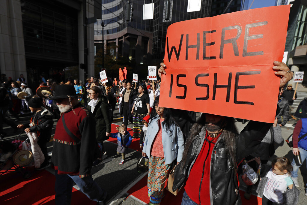 FILE - Dennis Willard, of Bellevue, Wash., carries a sign that reads "Where Is She" as he marches in support of missing and murdered indigenous women during a rally to mark Indigenous Peoples' Day in downtown Seattle, on Oct. 14, 2019. Washington Gov. Jay Inslee has signed into law a bill that creates a first-in-the-nation statewide alert system for missing Indigenous people. The law creates a system similar to Amber Alerts and so-called silver alerts, which are used respectively for missing children and vulnerable adults in many states. (AP Photo/Ted S.