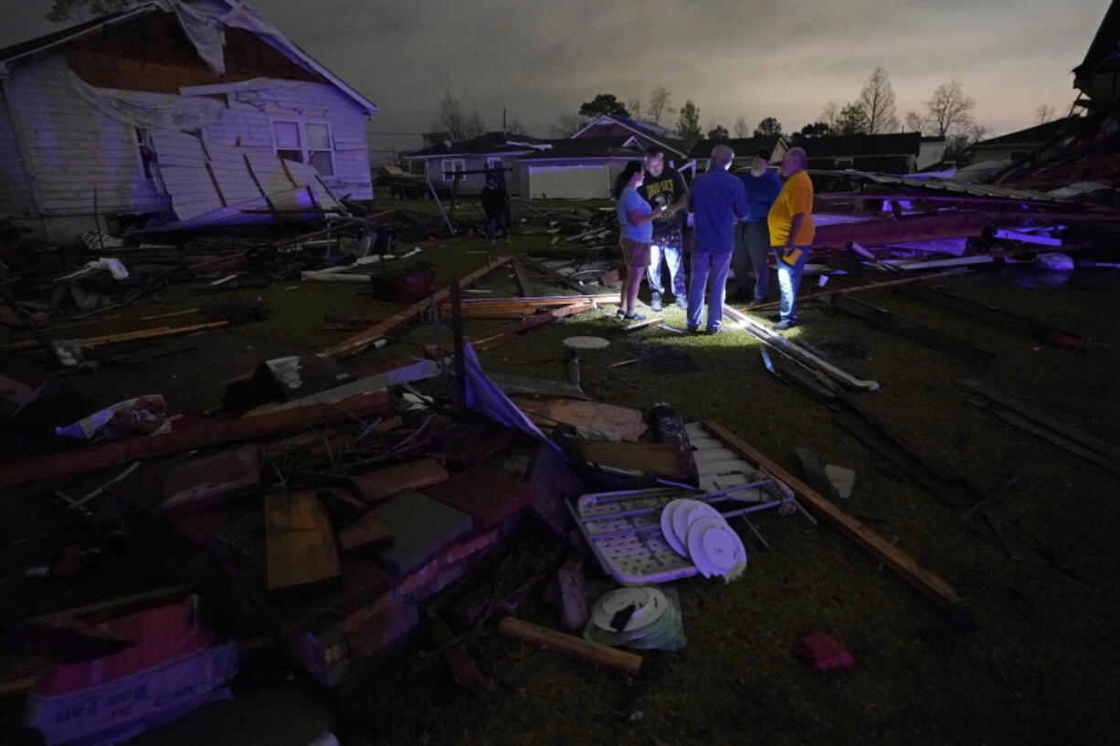 Christine Wiecek, left, and her husband Robert Patchus, second left, talk to neighbors amongst debris of their damaged homes after a tornado struck the area in Arabi, La., Tuesday, March 22, 2022. A tornado tore through parts of New Orleans and its suburbs Tuesday night, ripping down power lines and scattering debris in a part of the city that had been heavily damaged by Hurricane Katrina 17 years ago.