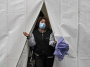 A woman wearing a face mask to help protect from the coronavirus walks out from a tent after getting a COVID-19 test, Tuesday, March 29, 2022, in Beijing. A two-phase lockdown of Shanghai's 26 million people is testing the limits of China's hard-line "zero-COVID" strategy, which is shaking markets far beyond the country's borders.