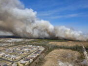 A fast-moving wildfire looms over homes outside of Panama City, Fla., Friday, March 4, 2022. More than 200 firefighters and emergency workers from throughout the Florida Panhandle worked overnight into Saturday, to strengthen containment lines and protect homes.