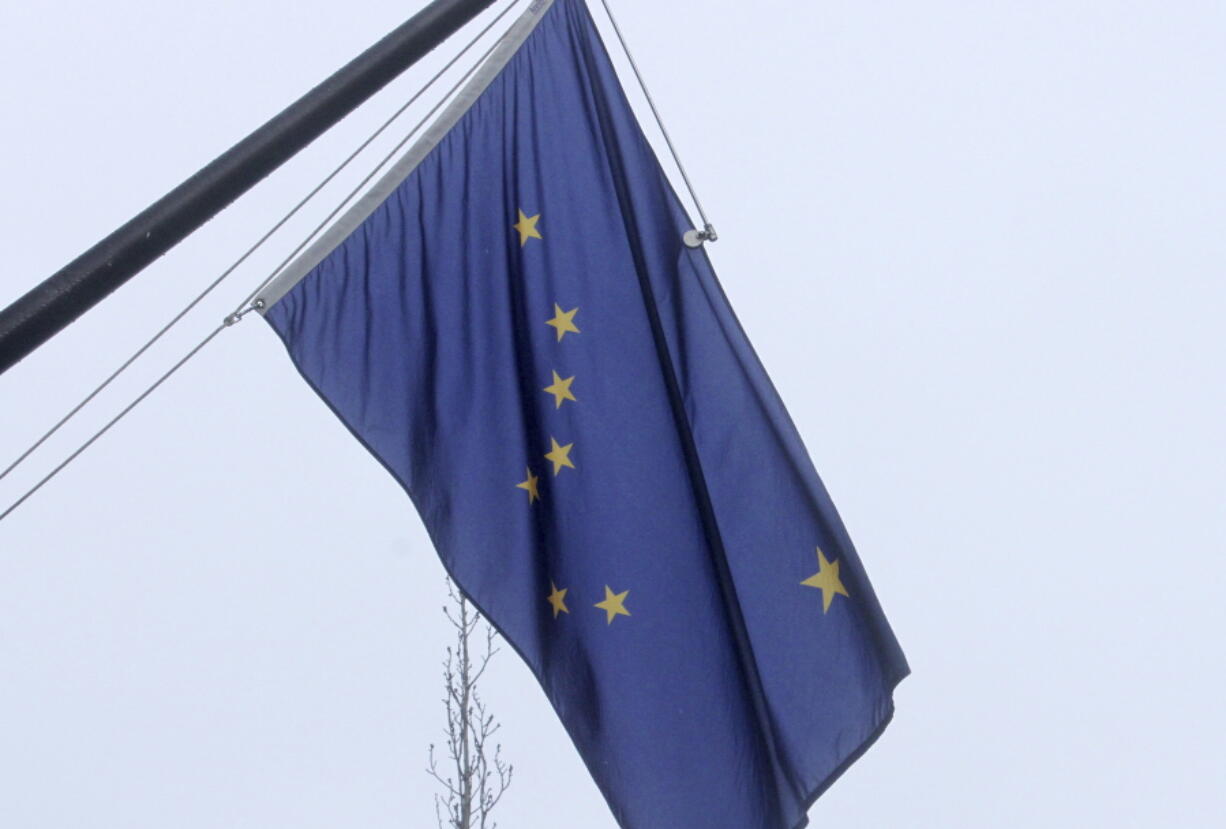 A state of Alaska flag flies outside the Atwood Building in downtown Anchorage, Alaska, on Friday, March 11, 2022. The state has issued a corrected birth certificate for Benny Benson, the teenager who won a design contest for the flag in 1927, meaning he was 14 and not 13 when came up with the design of the Big Dipper and the North Star on a simple field of blue.