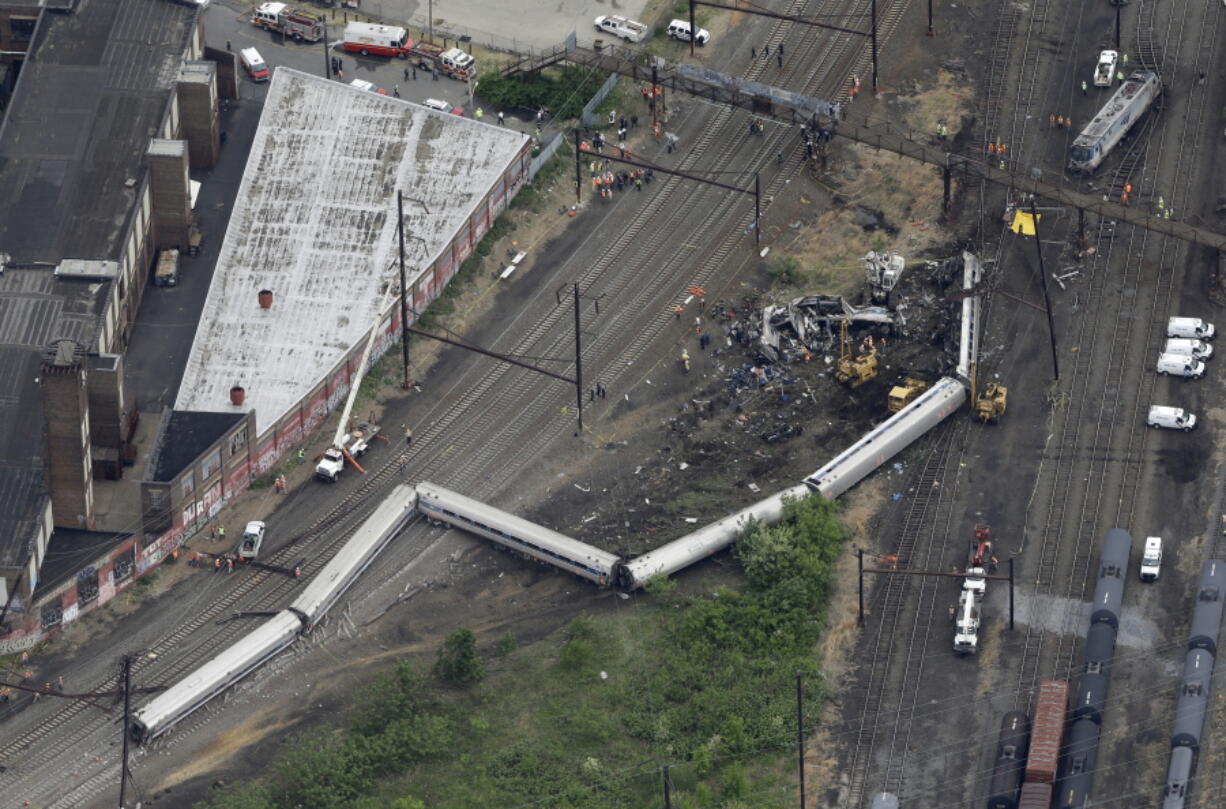 FILE- In this Wednesday, May 13, 2015, file photo, emergency personnel work at the scene of a derailment in Philadelphia of an Amtrak train headed to New York. A Philadelphia jury is expected weigh criminal charges Friday, March 4, 2022, against Amtrak engineer Brandon Bostian over the deadly derailment.