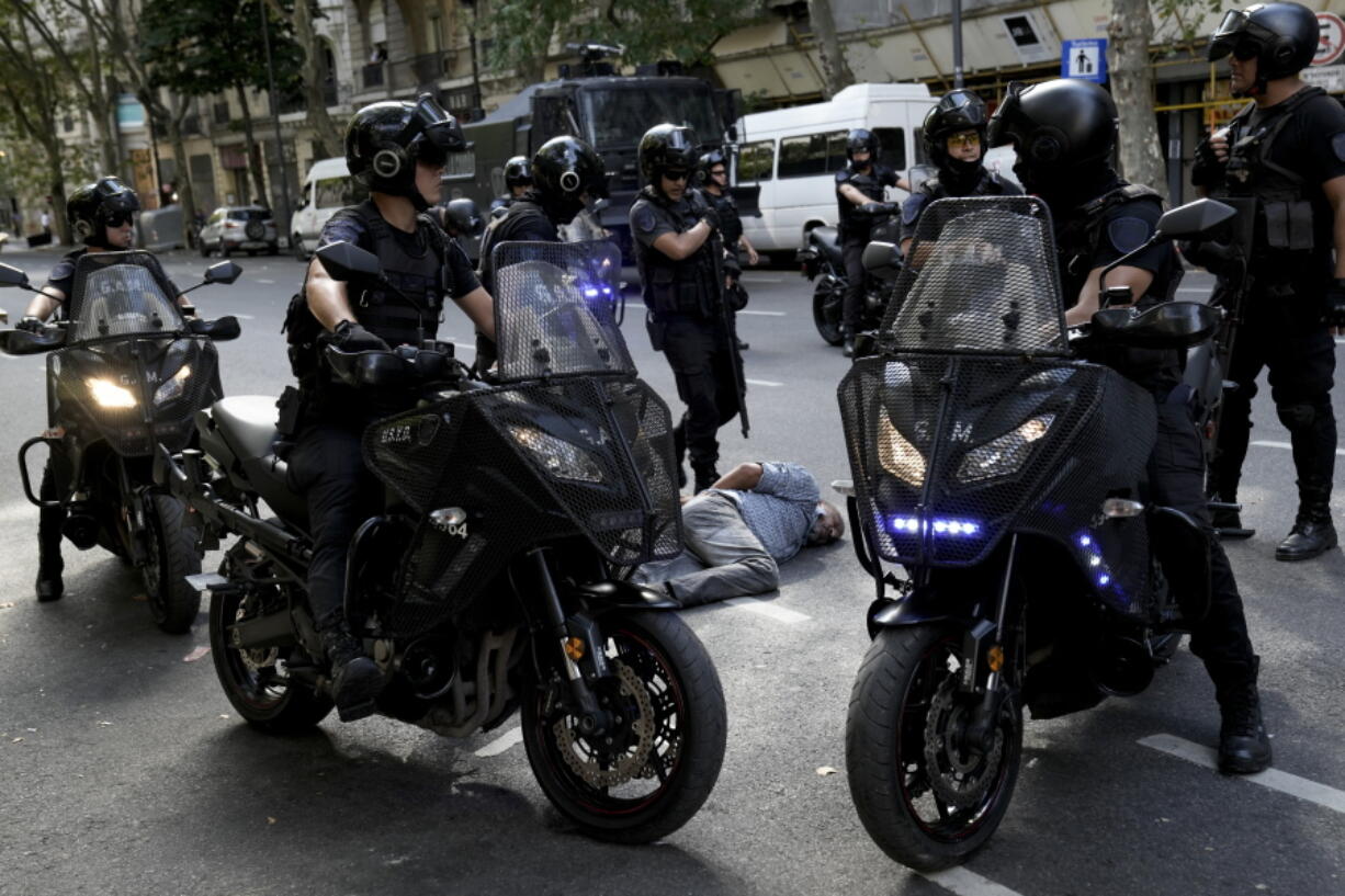 A detained demonstrator lies on the ground surrounded by police near Congress during clashes with demonstrators protesting the government's agreement with the International Monetary Fund to refinance some $45 billion in debt, as legislators prepare to vote on a law to ratify the agreement, in Buenos Aires, Argentina, Thursday, March 10, 2022.