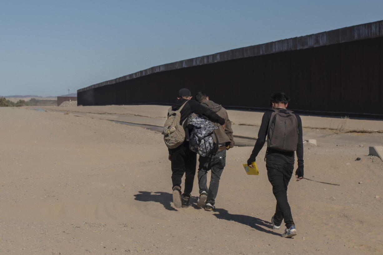 FILE - Nicaraguan migrants walk on the US-Mexico border, in Algodones, Baja California, Mexico, Dec. 2, 2021. The group walked into the U.S. and turned themselves over to the border patrol asking for asylum. The Biden administration has a draft plan to end sweeping asylum limits at the U.S.-Mexico border by May 23 that were put in place to prevent the spread of COVID-19, according to people familiar with the plans.