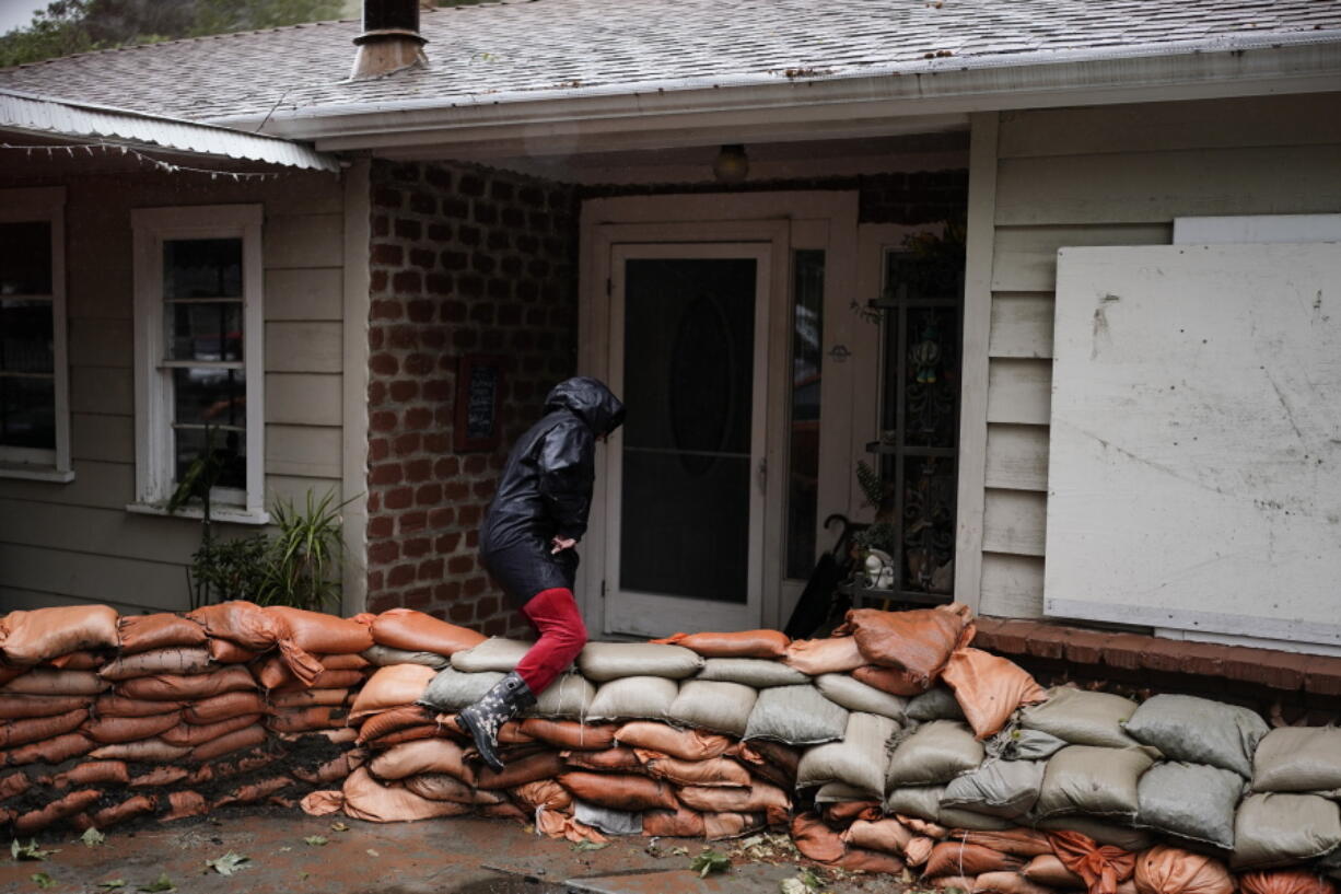 Bianca Kulback, 57, walks over sandbags stacked around her home during a rain storm in Silverado Canyon, Calif., Monday, March 28, 2022. A vigorous late-season storm moved slowly through California on Monday, bringing flood worries as rain fell across wildfire burn scars. (AP Photo/Jae C.