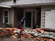 Bianca Kulback, 57, walks over sandbags stacked around her home during a rain storm in Silverado Canyon, Calif., Monday, March 28, 2022. A vigorous late-season storm moved slowly through California on Monday, bringing flood worries as rain fell across wildfire burn scars. (AP Photo/Jae C.