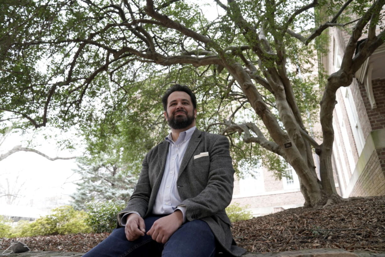 Benjamin Frey, American Studies professor at the University of North Carolina, sits under the native Ilex vomitoria tree on campus in Chapel Hill, N.C., Thursday, Feb. 24, 2022. Frey, a member of the Eastern Band of Cherokee Indians, led the language research behind a new smartphone interface by Lenovo-owned Motorola. The Cherokee language interface on its newest line of phones, uses the syllable-based written characters first created by the Cherokee Nation's Sequoyah in the early 1800s.