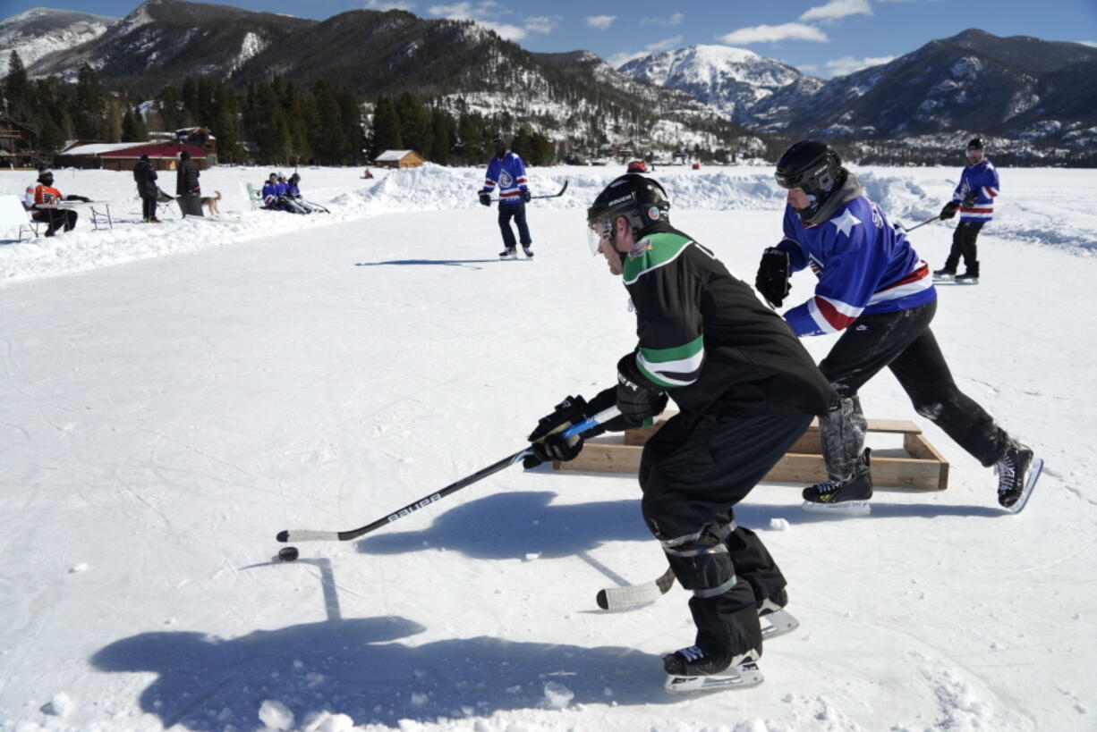 An athlete sweeps a puck behind a goal at a pond hockey tournament Feb. 26 in Grand Lake, Colo.