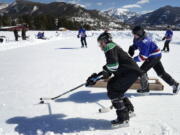 An athlete sweeps a puck behind a goal at a pond hockey tournament Feb. 26 in Grand Lake, Colo.