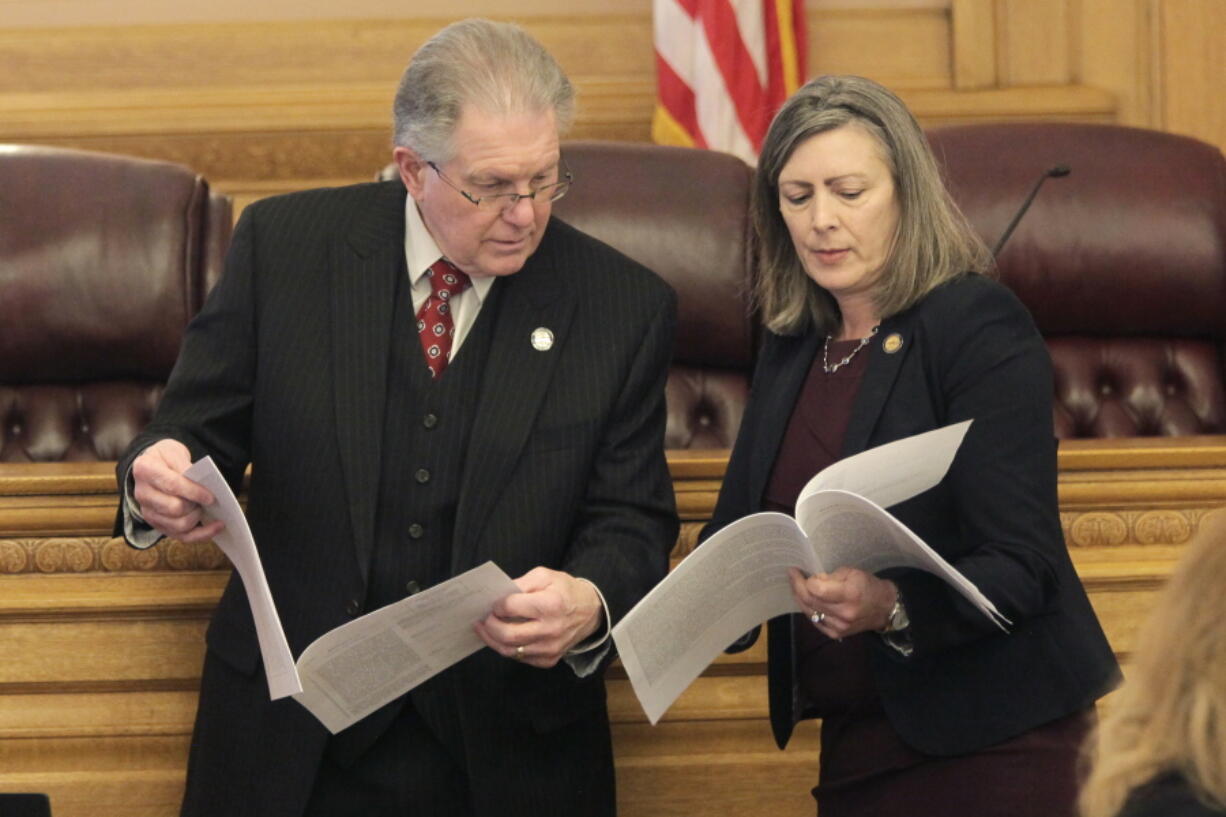 Kansas state Sen. Mike Thompson, left, R-Shawnee, confers with state Sen. Kellie Warren, R-Leawood, Wednesday, March 9, 2022, during a committee meeting at the Statehouse in Topeka, Kan. Thompson denies the link between human activity and climate change and has a key role in energy policy as the Senate Utilities Committee chairman.