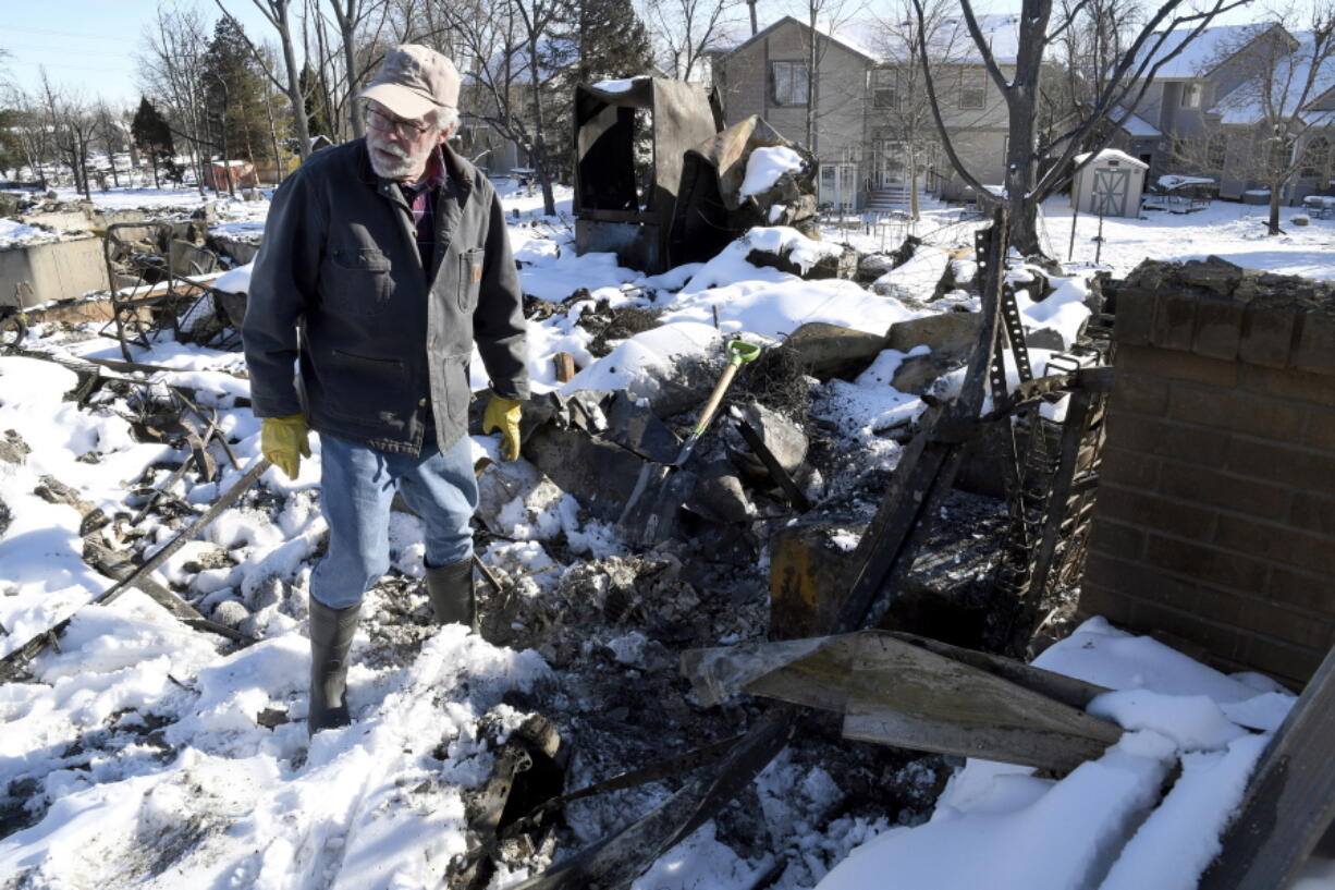 FILE - Rex Hickman sifts through the rubble of his burned home in Louisville, Colo., Sunday, Jan. 2, 2022. Some homeowners recovering from Colorado's most destructive wildfire in history, which decimated entire neighborhoods near Denver late last year, say they could end up paying tens of thousands of dollars more to rebuild because of environmentally sustainable construction standards passed shortly before the blaze.