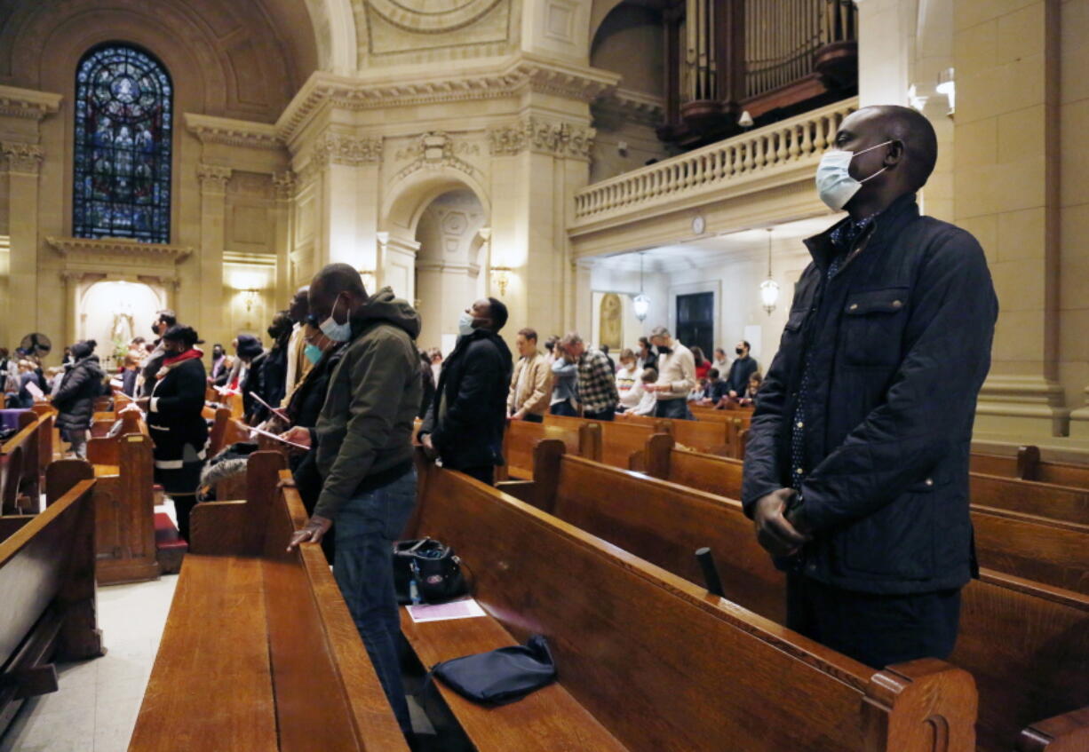 Paul Ndong, right, joins dozens of parishioners for a French Mass at the Church of Notre Dame in New York, on Sunday, March 6, 2022. Many parishioners come from former French and Belgium colonies in West and Central Africa, like Senegal, Ivory Coast, Mali, Togo and Congo.